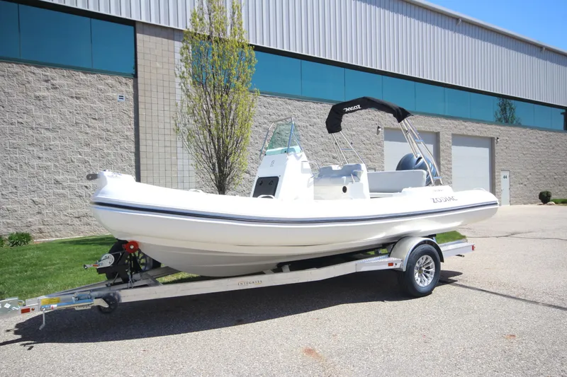 Slide: The Image of 2025 Zodiac Medline 5.8 NEO boat on trailer, parked outside industrial building. - 5
