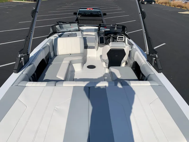 Slide: The Image of 2024 Malibu LX-R boat interior with white and gray seating, parked in a lot. - 12