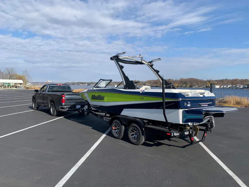 Slide: The Image of 2024 Malibu LX-R boat on trailer, hitched to a truck in a parking lot. - 7