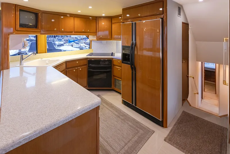 Slide: The Image of Modern kitchen interior on a 2000 Viking 72 Convertible yacht with wood cabinetry and granite countertops. - 15