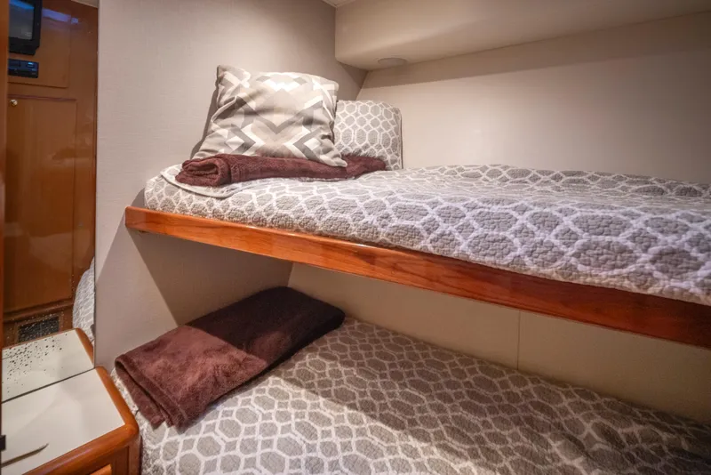 Slide: The Image of Bunk beds in the 2000 Viking 72 Convertible yacht cabin, featuring patterned bedding and wooden frames. - 27