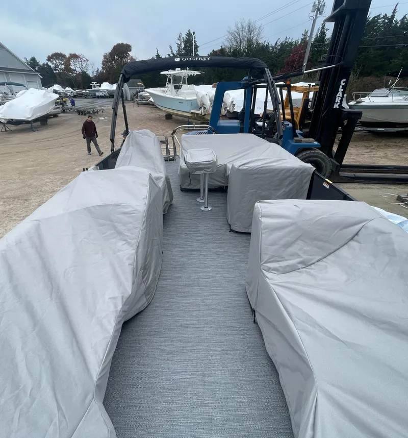 Slide: The Image of 2023 Godfrey Monaco 235 SFL pontoon boat with covered seating, docked in a marina. - 22