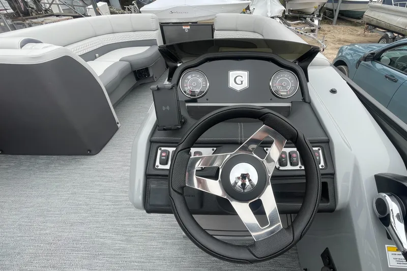 Slide: The Image of 2023 Godfrey Monaco 235 SFL boat dashboard with steering wheel and control panel. - 24