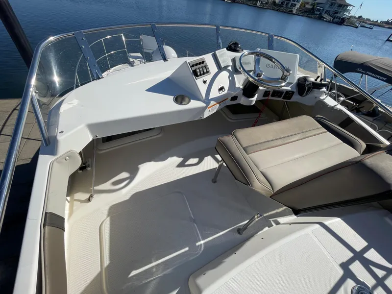 Slide: The Image of 2022 Cutwater Flybridge boat helm with steering wheel and seating, docked by the water. - 12
