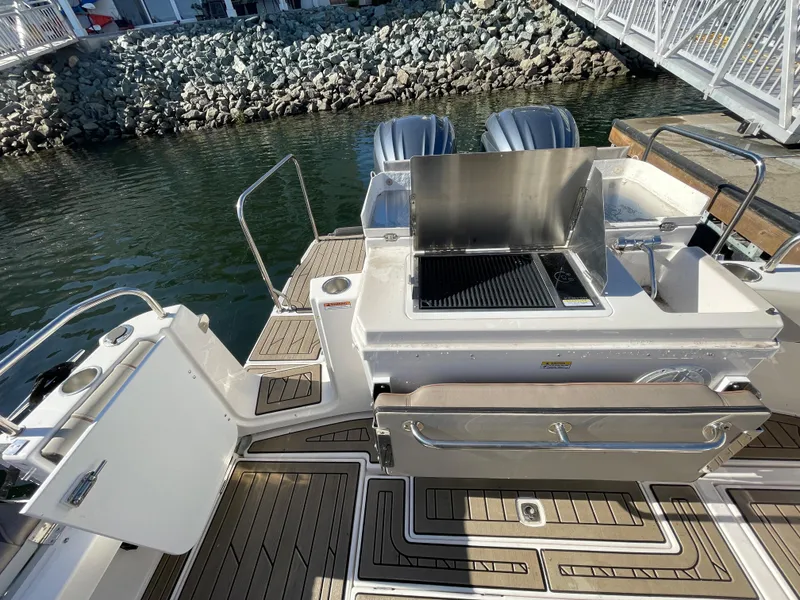 Slide: The Image of 2022 Cutwater Flybridge boat with outdoor grill and twin engines, docked by rocky shoreline. - 17