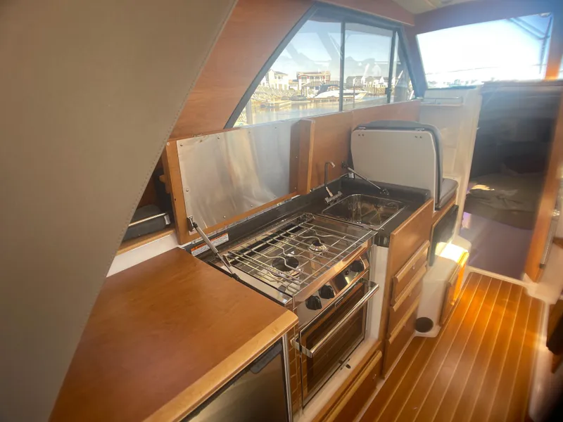 Slide: The Image of 2022 Cutwater Flybridge interior with modern kitchen, featuring stove and wooden cabinetry. - 22