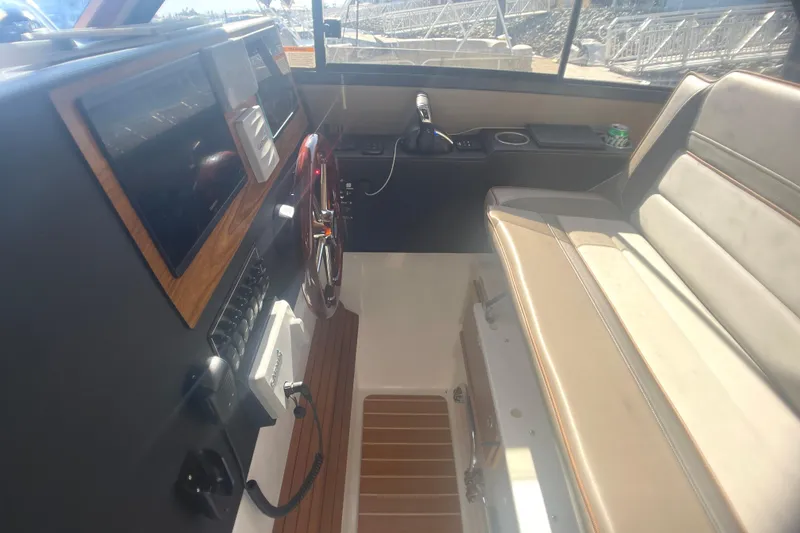 Slide: The Image of 2022 Cutwater Flybridge interior with steering wheel, dashboard, and beige seating. - 29