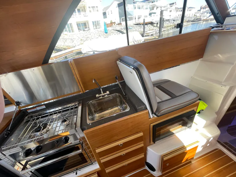 Slide: The Image of 2022 Cutwater Flybridge interior with kitchenette, stove, sink, and seating, showcasing modern design. - 3