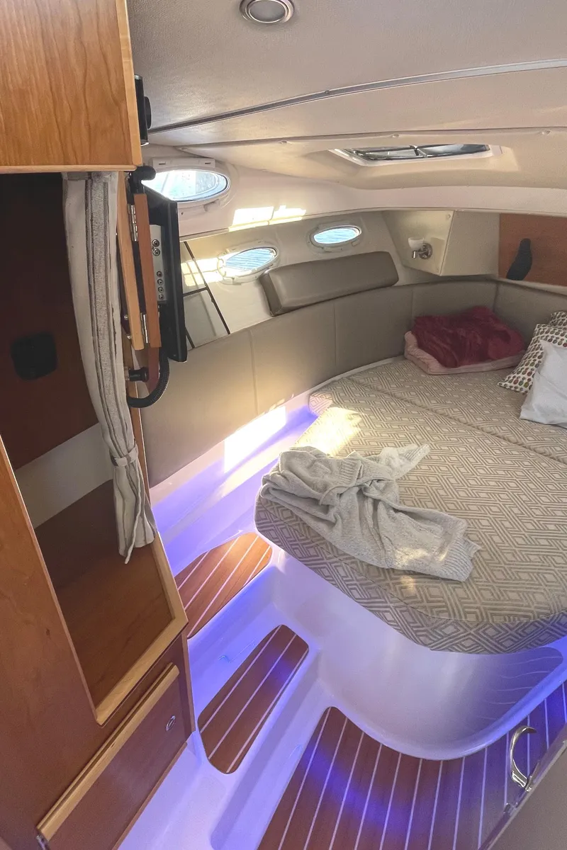 Slide: The Image of 2022 Cutwater Flybridge interior with cozy bed, ambient lighting, and wooden accents. - 7