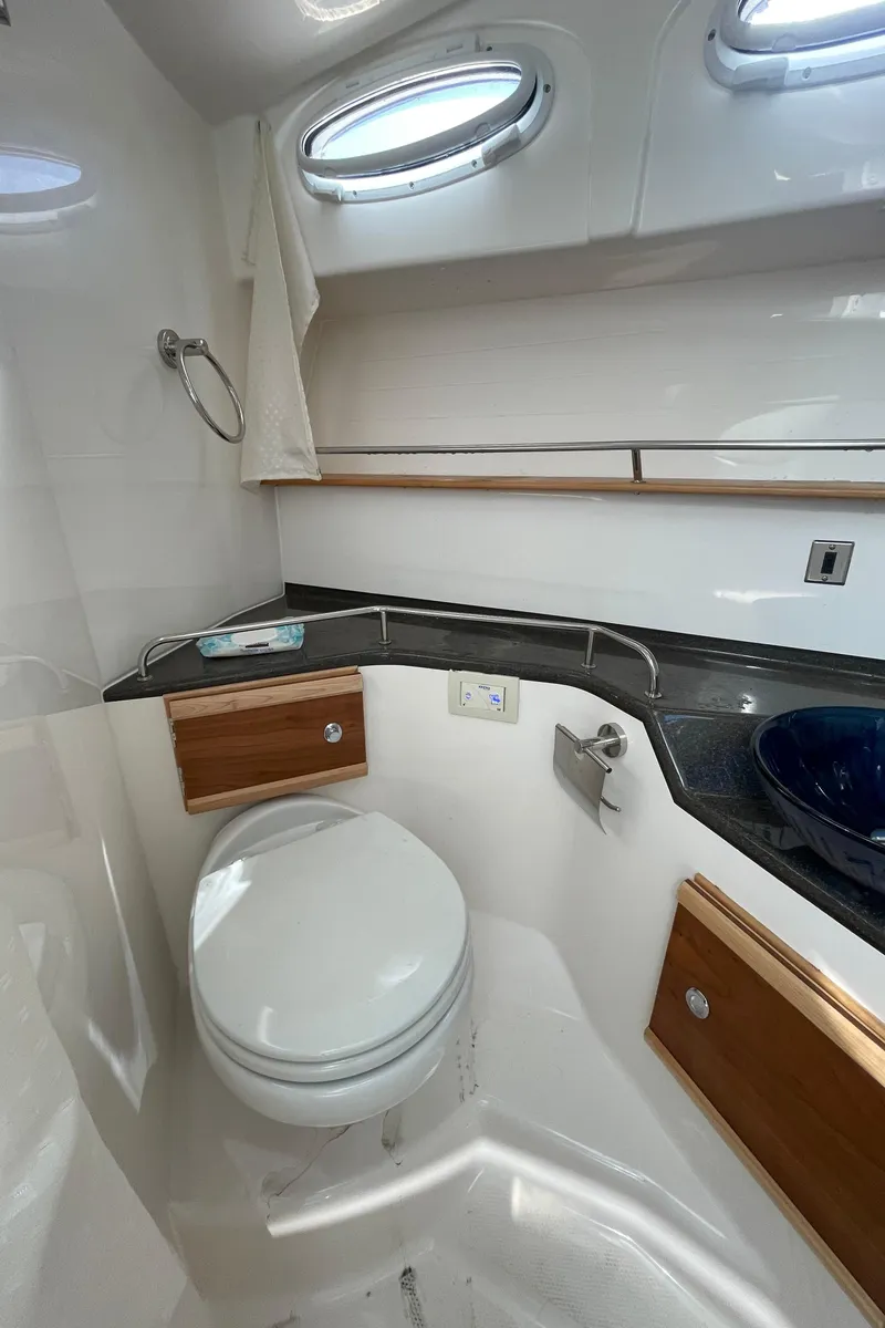 Slide: The Image of 2022 Cutwater Flybridge bathroom with modern fixtures, porthole windows, and wooden cabinetry. - 8
