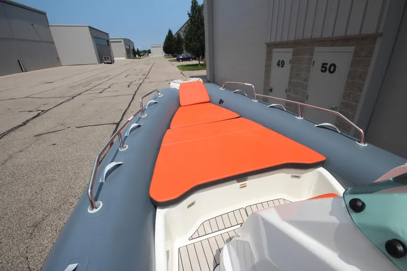 Slide: The Image of 2024 Zodiac Medline 7.5 NEO boat with orange seating, docked near industrial buildings. - 32