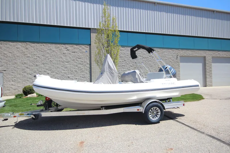 Slide: The Image of 2025 Zodiac Medline 5.8 NEO boat on trailer, parked outside industrial building. - 2