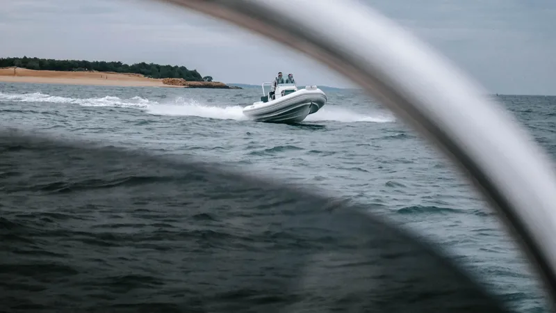 Slide: The Image of 2025 Zodiac Medline 5.8 NEO boat cruising on open water near a sandy shoreline. - 24