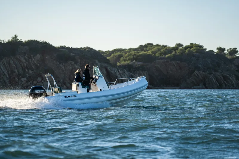 Slide: The Image of Zodiac Medline 5.8 NEO 2025 boat cruising on water near rocky shoreline. - 26