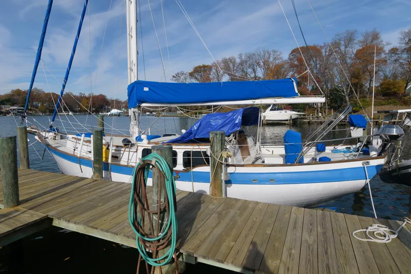 The Image of 1976 Downeast 38 sailboat docked at a marina with blue and white accents. - 0