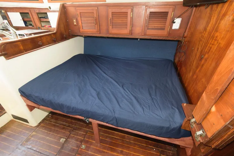 Slide: The Image of 1976 Downeast 38 boat interior cabin with wooden furnishings and a blue mattress. - 11