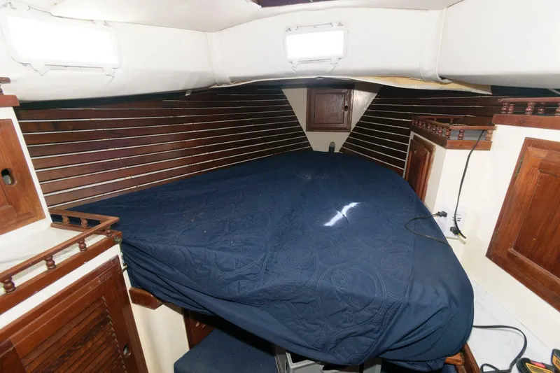 Slide: The Image of 1976 Downeast 38 boat cabin with wooden paneling and a blue bedspread. - 12