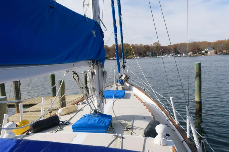 Slide: The Image of 1976 Downeast 38 sailboat docked at a marina with blue sail covers. - 3