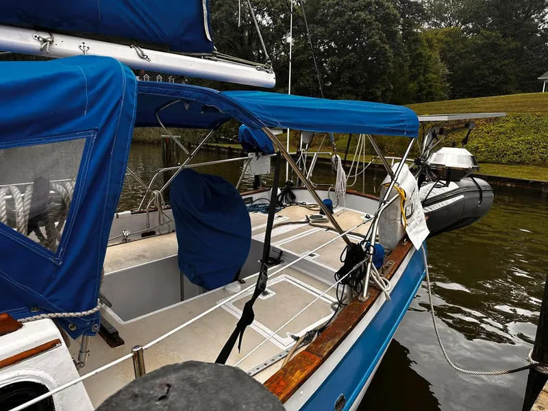 Slide: The Image of 1976 Downeast 38 sailboat docked, featuring blue canvas covers and a well-maintained deck. - 4