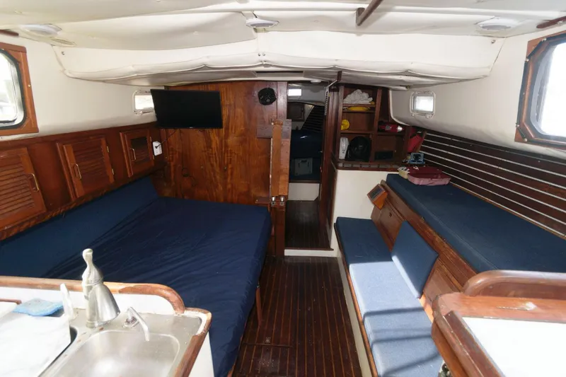 Slide: The Image of 1976 Downeast 38 sailboat interior with wooden finishes and blue seating. - 8