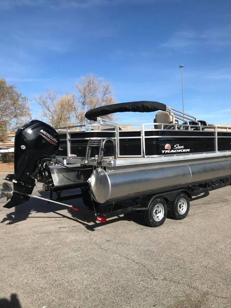 Slide: The Image of 2024 Sun Tracker SportFish 20 DLX pontoon boat on trailer, outdoor setting. - 2
