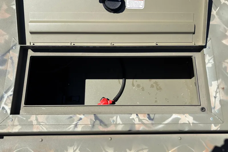 Slide: The Image of Open storage compartment of 2024 Tracker Grizzly 1754 SC boat, featuring camouflage design. - 26