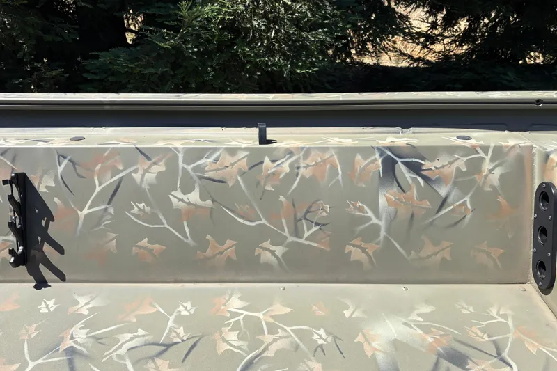 Slide: The Image of 2024 Tracker Grizzly 1754 SC boat with camouflage pattern, featuring rod holders and outdoor setting. - 25