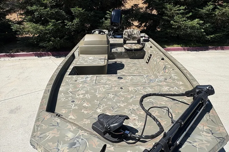 Slide: The Image of 2024 Tracker Grizzly 1754 SC boat with camouflage design, parked outdoors. - 13
