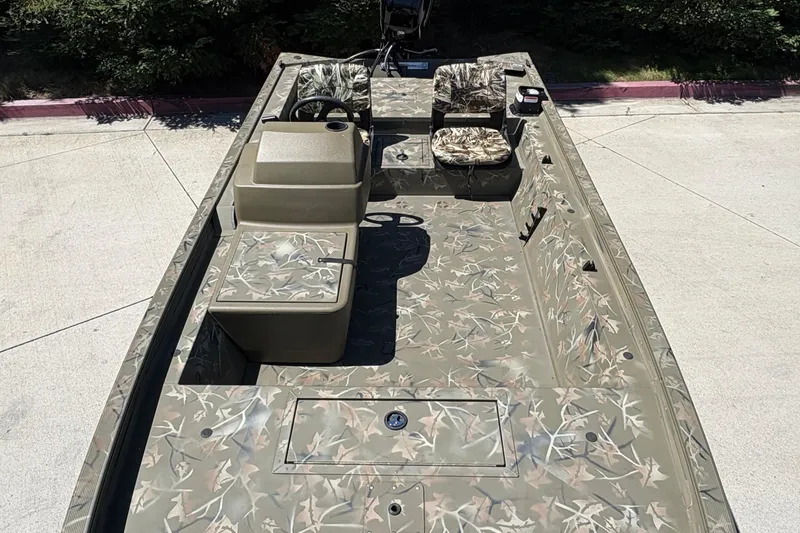 Slide: The Image of 2024 Tracker Grizzly 1754 SC boat with camouflage interior design, parked outdoors. - 16