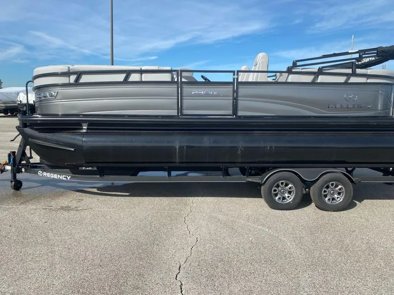 Slide: The Image of 2024 Regency 230 DL3 pontoon boat on a trailer in a parking lot. - 0