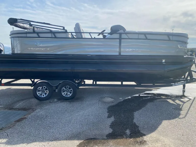 Slide: The Image of 2024 Regency 230 DL3 pontoon boat on a trailer in a parking lot. - 1