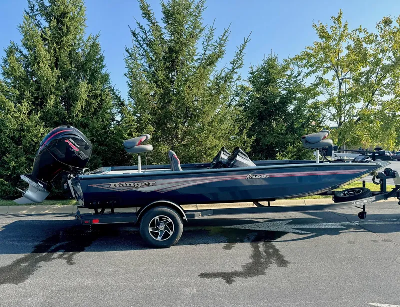 The Image of 2024 Ranger RT198P boat on trailer, parked outdoors, surrounded by trees. - 0