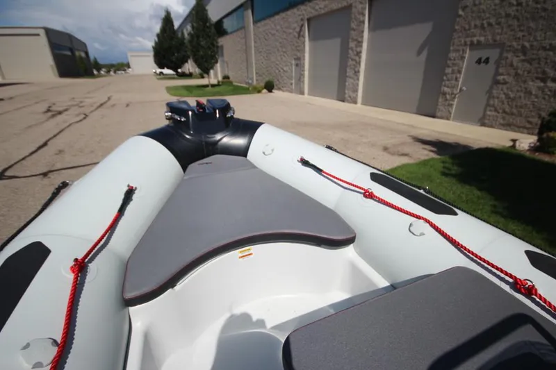 Slide: The Image of 2024 Zodiac Open 4.8 NEO 70hp inflatable boat in stock, docked near industrial buildings. - 16