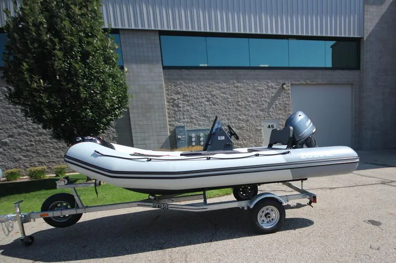 Slide: The Image of 2024 Zodiac Open 4.8 NEO 70hp boat on trailer outside industrial building. - 3