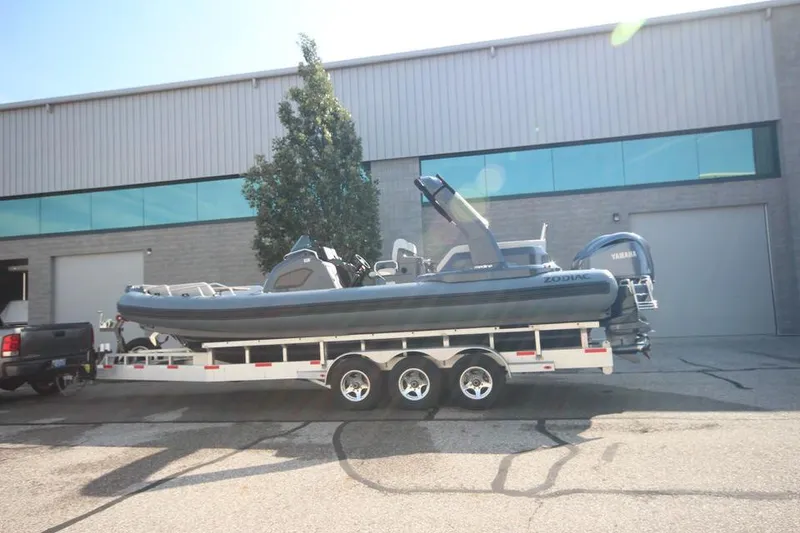 The Image of 2024 Zodiac MEDLINE 9 NEO boat on trailer, twin 300hp engines, parked outside warehouse. - 0