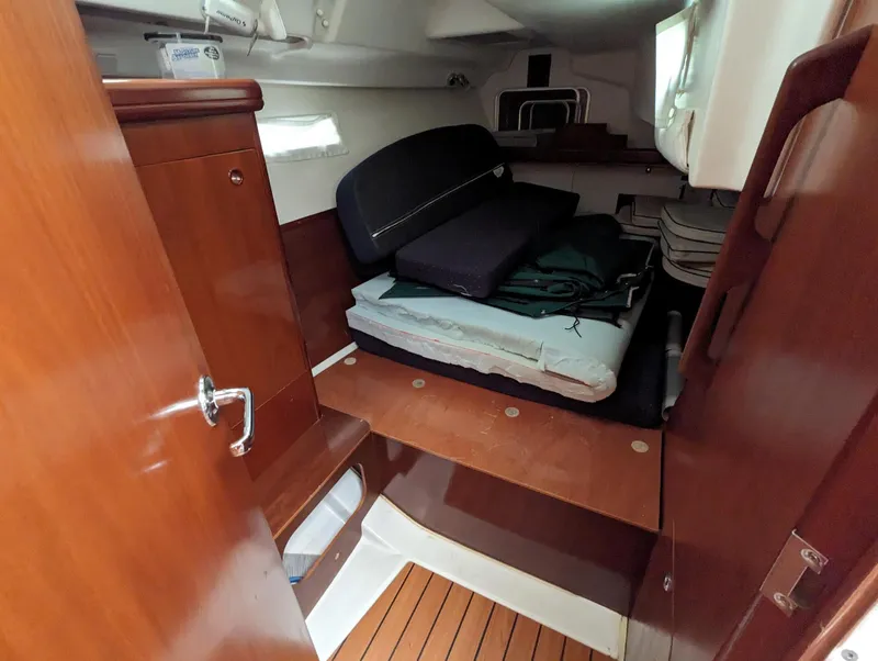 Slide: The Image of 2005 Beneteau 393 interior cabin with wooden finish and stacked cushions. - 12