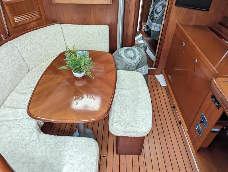 Slide: The Image of Interior of 2005 Beneteau 393 yacht with wooden table, cushioned seating, and potted plant. - 14