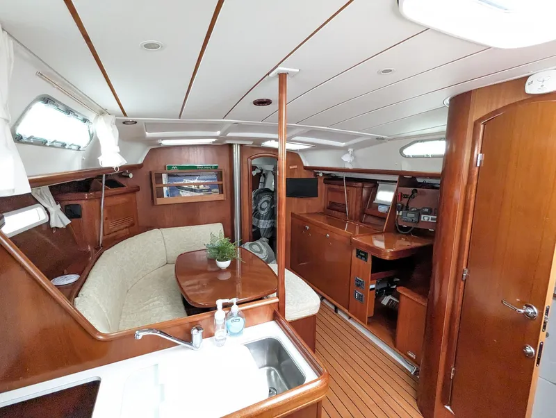 Slide: The Image of 2005 Beneteau 393 yacht interior with wood finish, dining area, and kitchenette. - 21