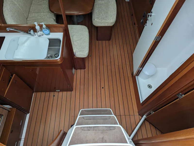 Slide: The Image of Interior of 2005 Beneteau 393 yacht with wooden flooring and compact kitchen area. - 3