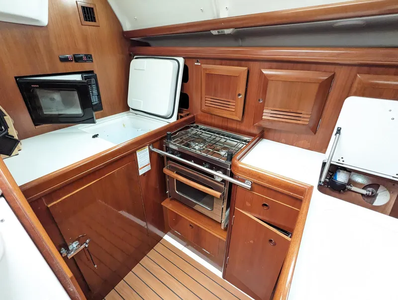Slide: The Image of Galley kitchen in 2005 Beneteau 393 sailboat with wood cabinetry and modern appliances. - 4