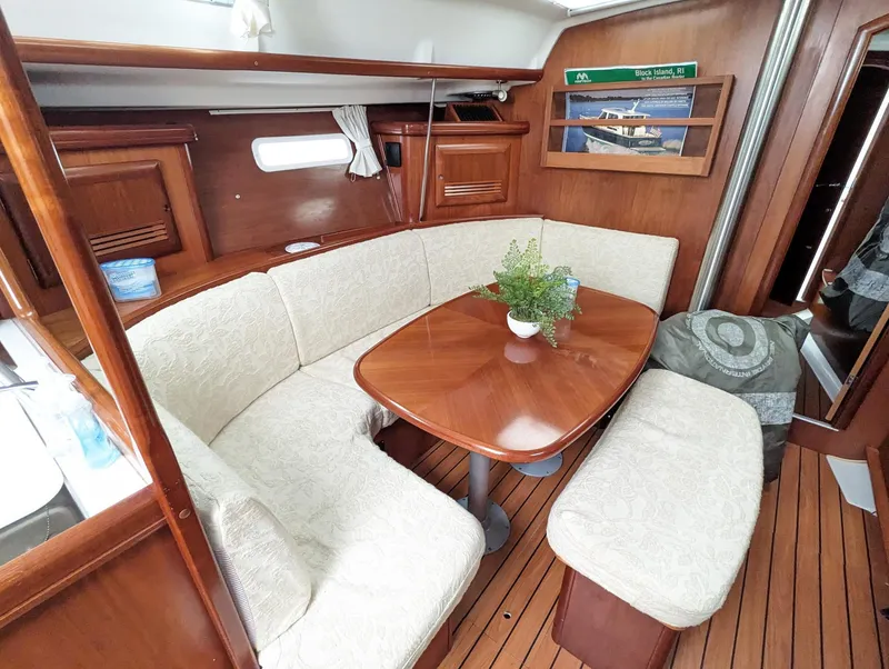 Slide: The Image of Cozy interior of 2005 Beneteau 393 sailboat with wooden table and cushioned seating. - 5