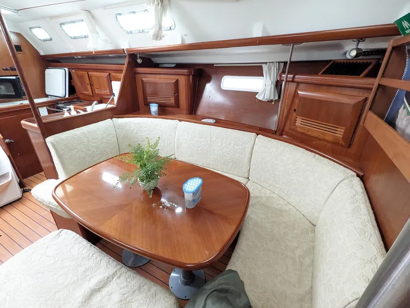 Slide: The Image of Interior of 2005 Beneteau 393 yacht with cozy dining area and wooden furnishings. - 8