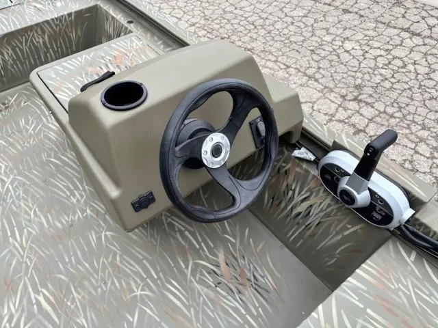 Slide: The Image of 2024 Tracker Grizzly 1648 SC boat steering console with camouflage design. - 10