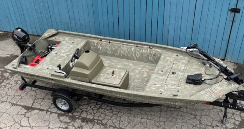 Slide: The Image of 2024 Tracker Grizzly 1648 SC boat on trailer, parked by blue wooden fence. - 4