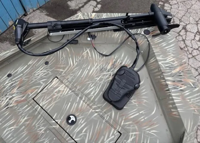 Slide: The Image of 2024 Tracker Grizzly 1648 SC boat with camouflage design and trolling motor. - 6