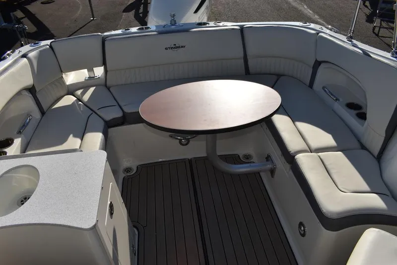 Slide: The Image of 2024 Stingray 231DC boat interior with cushioned seating and round table. - 48