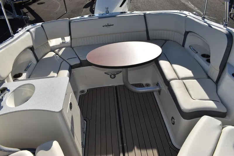 Slide: The Image of 2024 Stingray 231DC boat interior with cushioned seating and round table. - 49