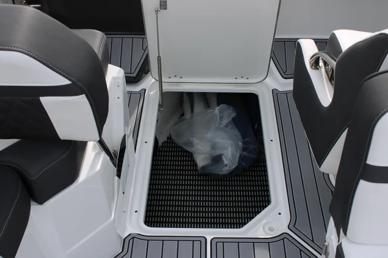 Slide: The Image of 2023 Monterey M6 boat storage compartment with open hatch and black-and-white seating. - 30