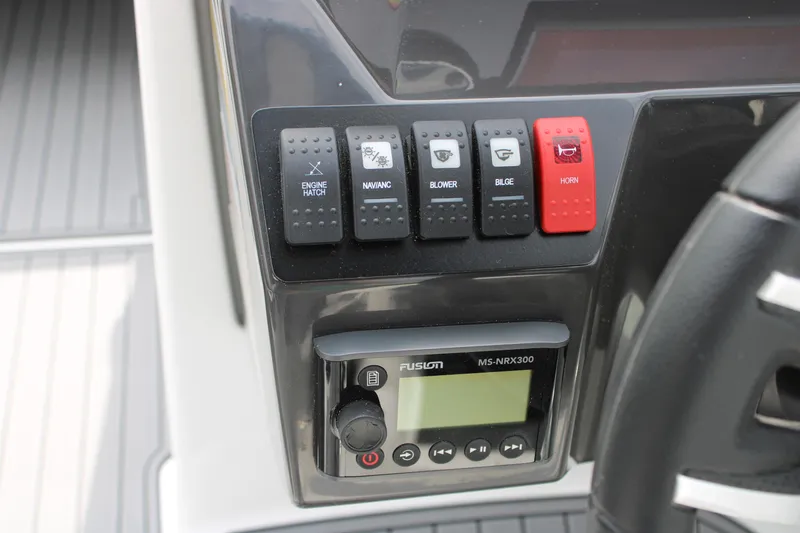 Slide: The Image of Control panel of a 2023 Monterey M6 boat with various switches and a Fusion MS-NRX300. - 37