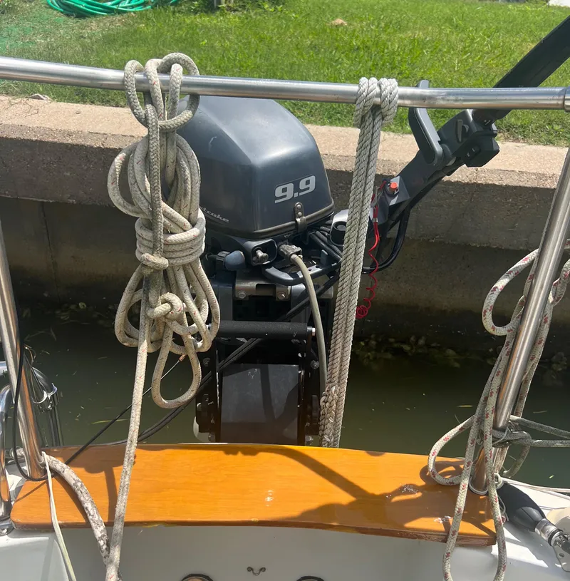 Slide: The Image of Outboard motor on a 1974 CAL T2 sailboat docked by a grassy area. - 23
